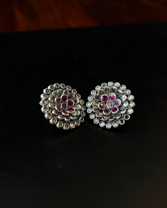 Pair of silver earrings with gemstones on a black background