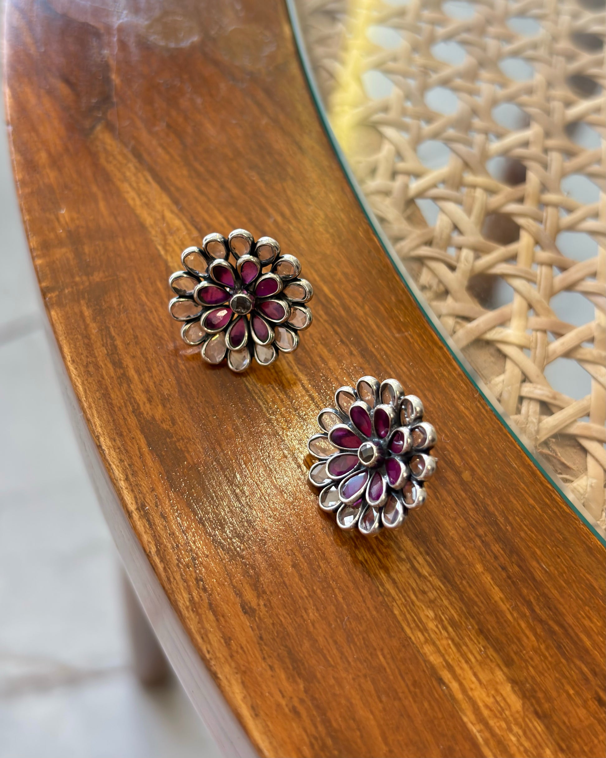Floral silver and red earrings on a wooden surface