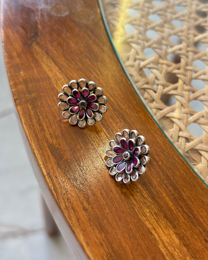 Floral silver and red earrings on a wooden surface