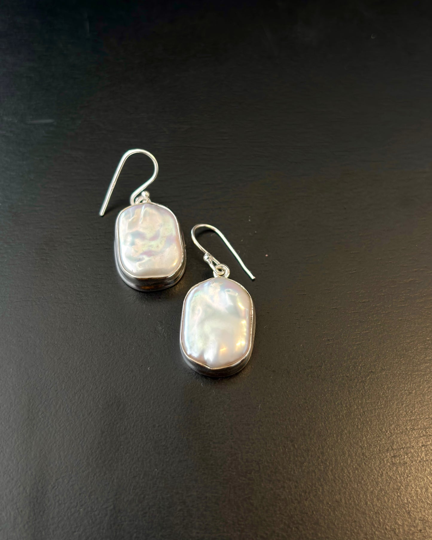 Pair of silver earrings with real water pearl on a dark surface, 92.5 silver
