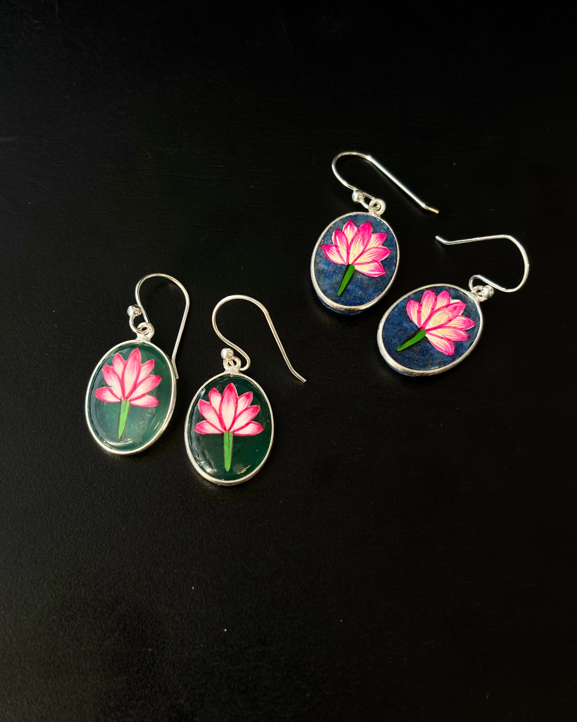 Pair of earrings with pink flower design on a black background