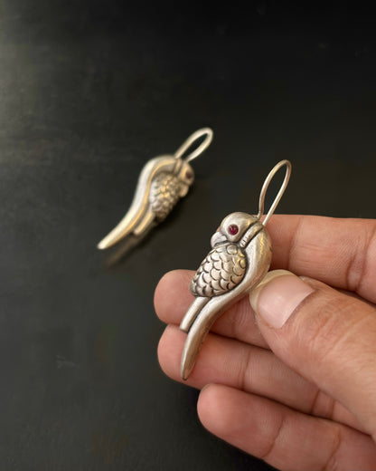 Silver parrot-shaped earring held by a hand against a dark background, 92.5 Silver Earrings, Silver parrot earrings