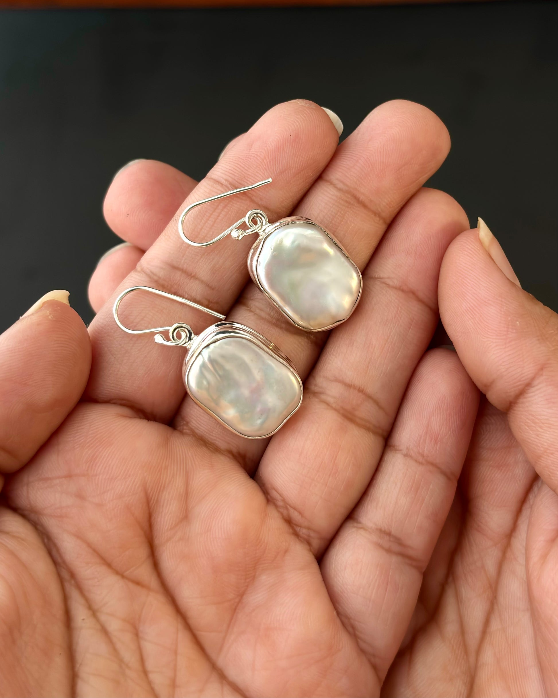 Pair of silver earrings with real water pearl on a dark surface, 92.5 silver