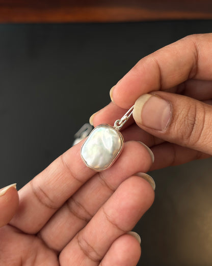Pair of silver earrings with real water pearl on a dark surface, 92.5 silver