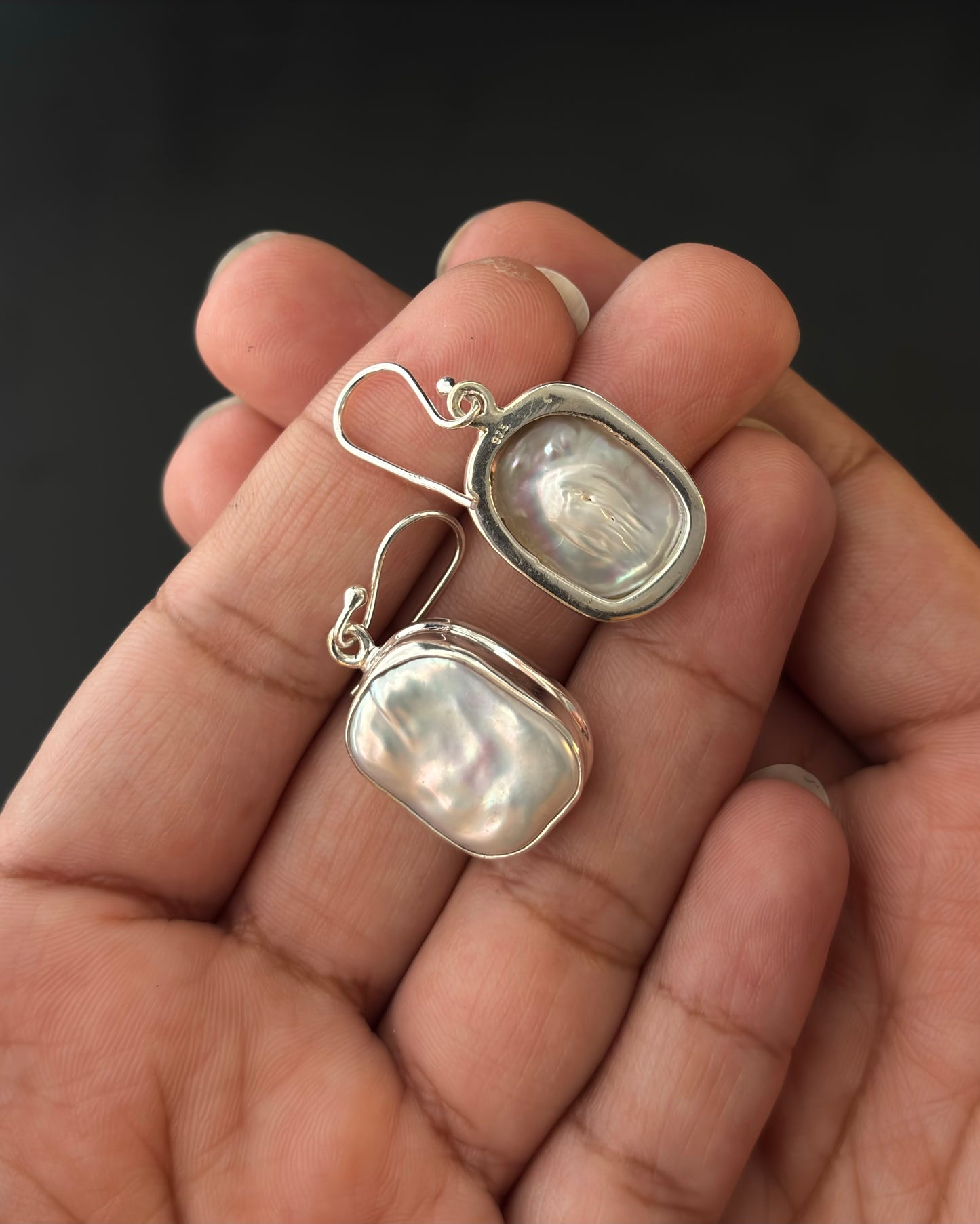 Pair of silver earrings with real water pearl on a dark surface, 92.5 silver