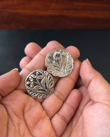 Two silver floral designs held in a hand against a dark background,  92.5 silver earrings