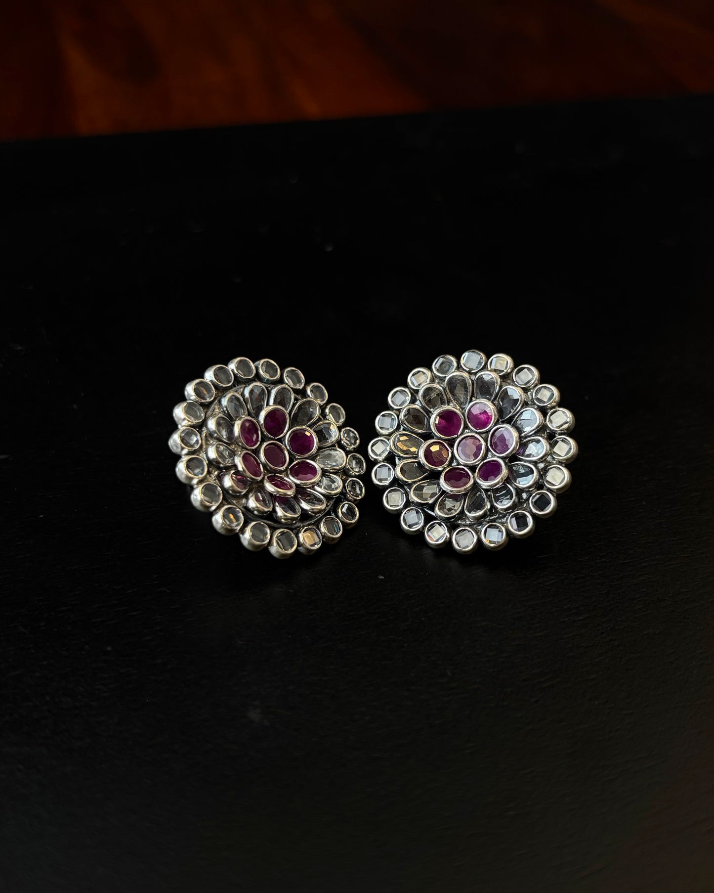 Pair of silver earrings with gemstones on a black background