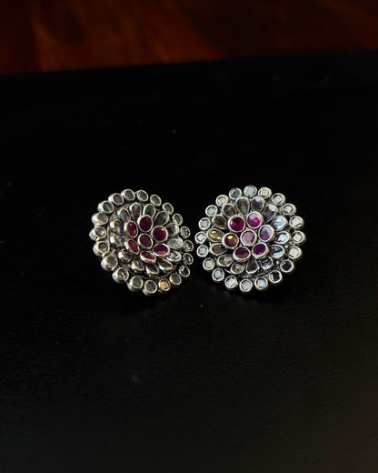 Pair of silver earrings with gemstones on a black background